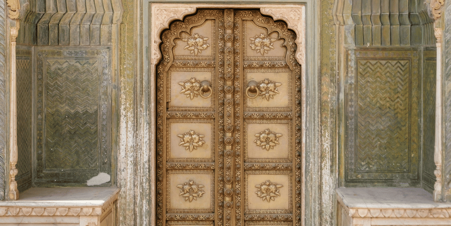 A door of Jaipur City Palace showcasing intricate designs on the door and around it.