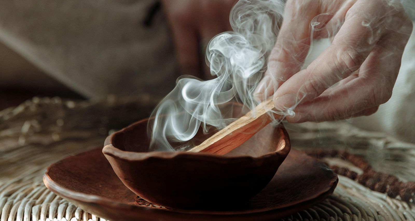 a person sitting on a huge mat burning incense sticks into a bowl