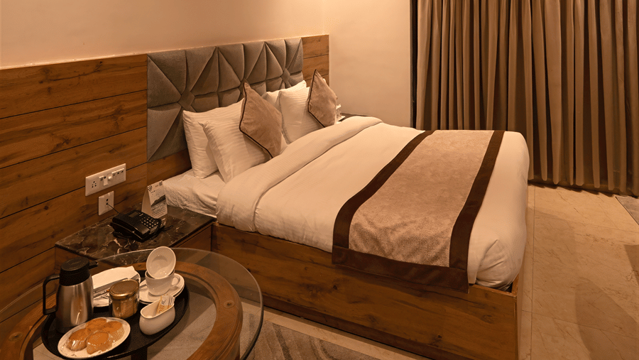 Cosy resort cottage bedroom featuring a double bed, vaulted wooden panel ceiling, and bedside coffee table - Wood Castle Spa & Resort, Jim Corbett