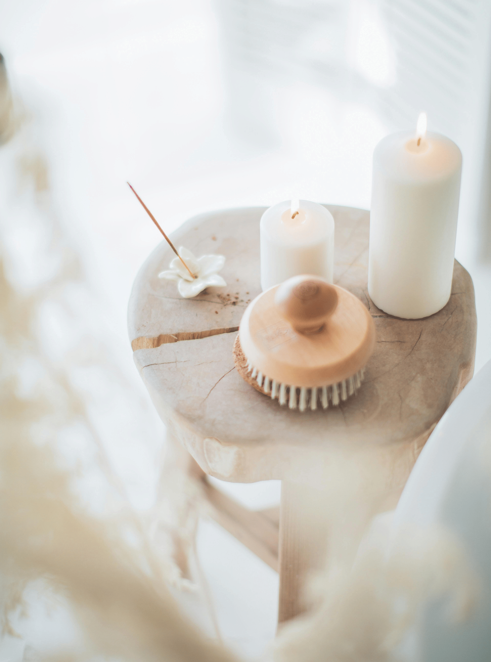 Spa setting with candles, towels, and a brush, immersed in a white background.
