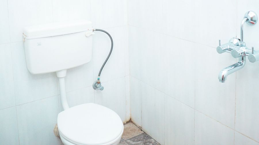 image of a brightly lit washroom with a commode and a geyser above it 