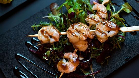 A beautifully arranged plate of prawns garnished with fresh herbs.