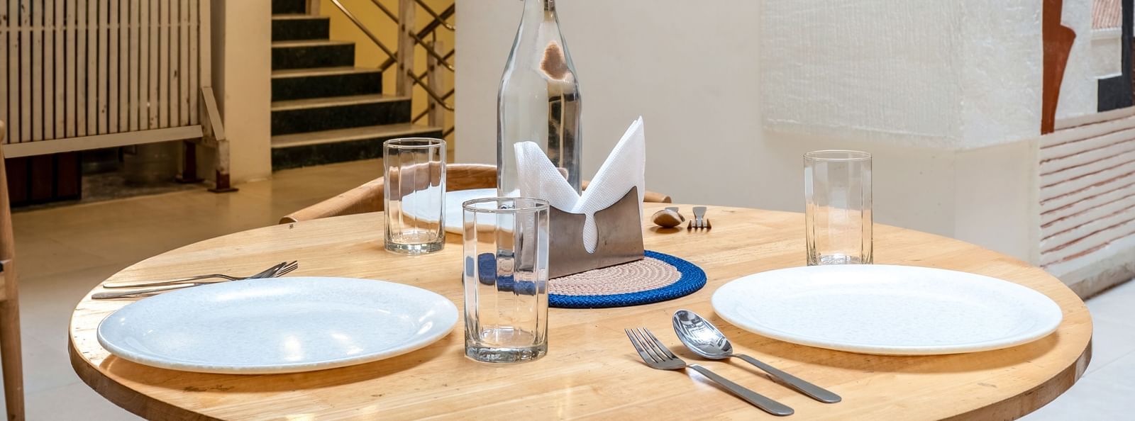 A round dining table set for 2 with plates, glasses, and cutlery - Monday Hotels HITEC City, Hyderabad