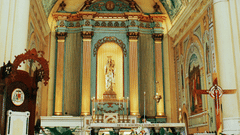 Ornate church interior with painted ceilings, arched columns, and an altar.