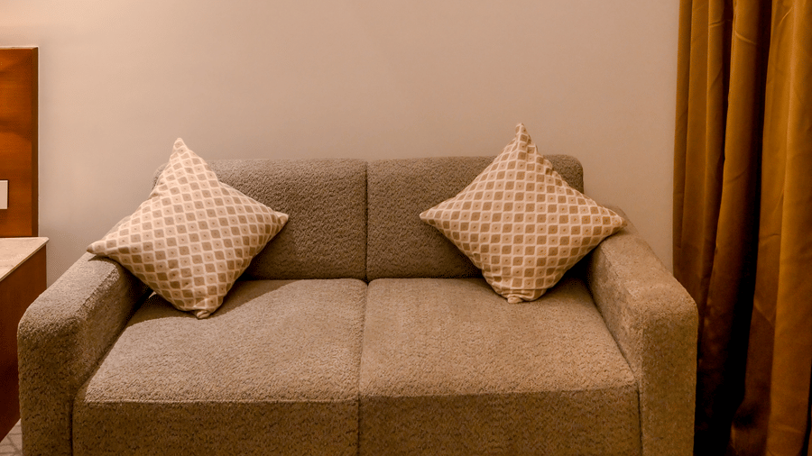 A compact seating area containing a 2 seater sofa under a framed painting on the wall at Tiara by MPS.