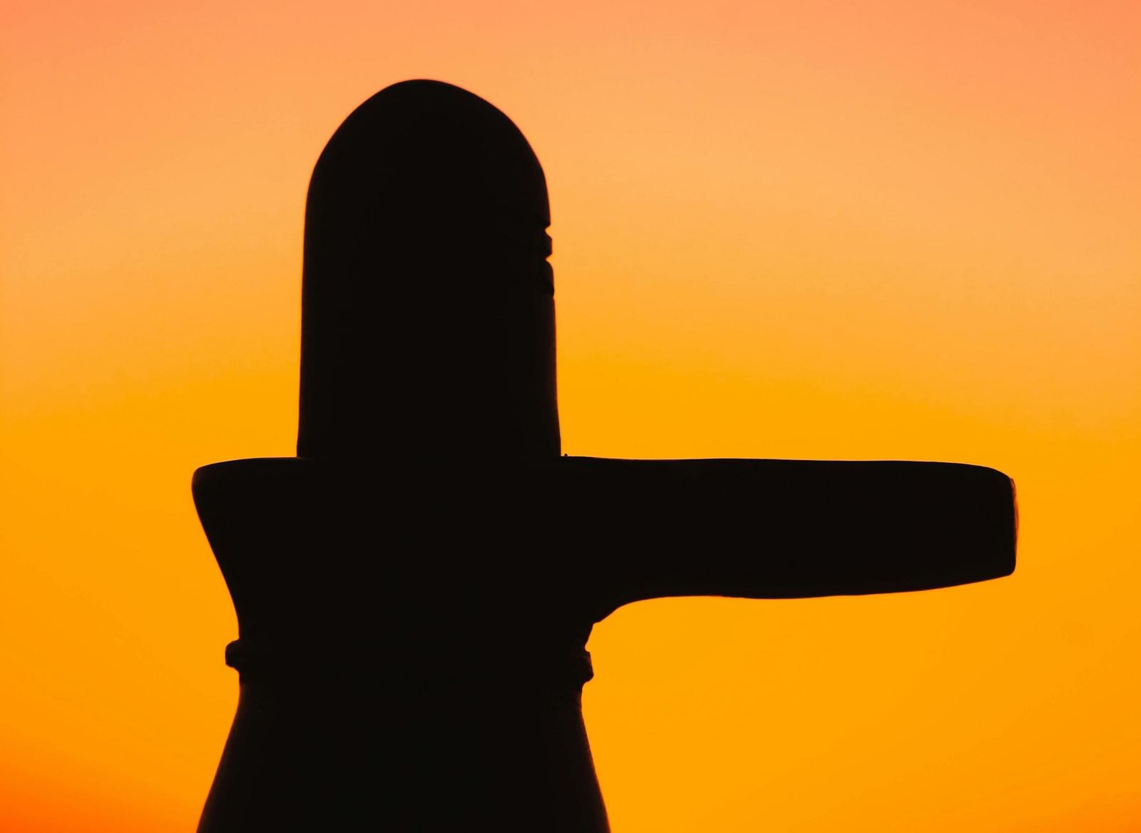A silhouetted figure of a religious symbol, set against the backdrop of a bright, colourful sunset.