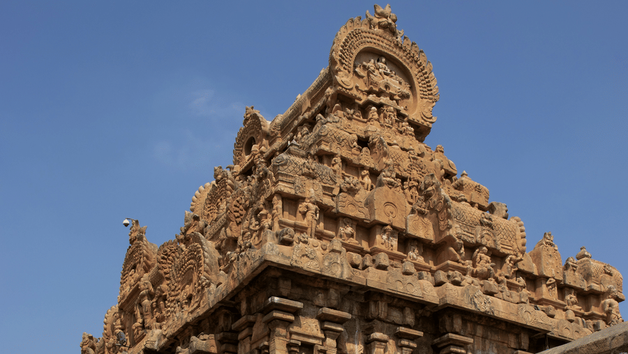 Brihadeeswara Temple under a blue sky featuring intricate carvings on a sunny day