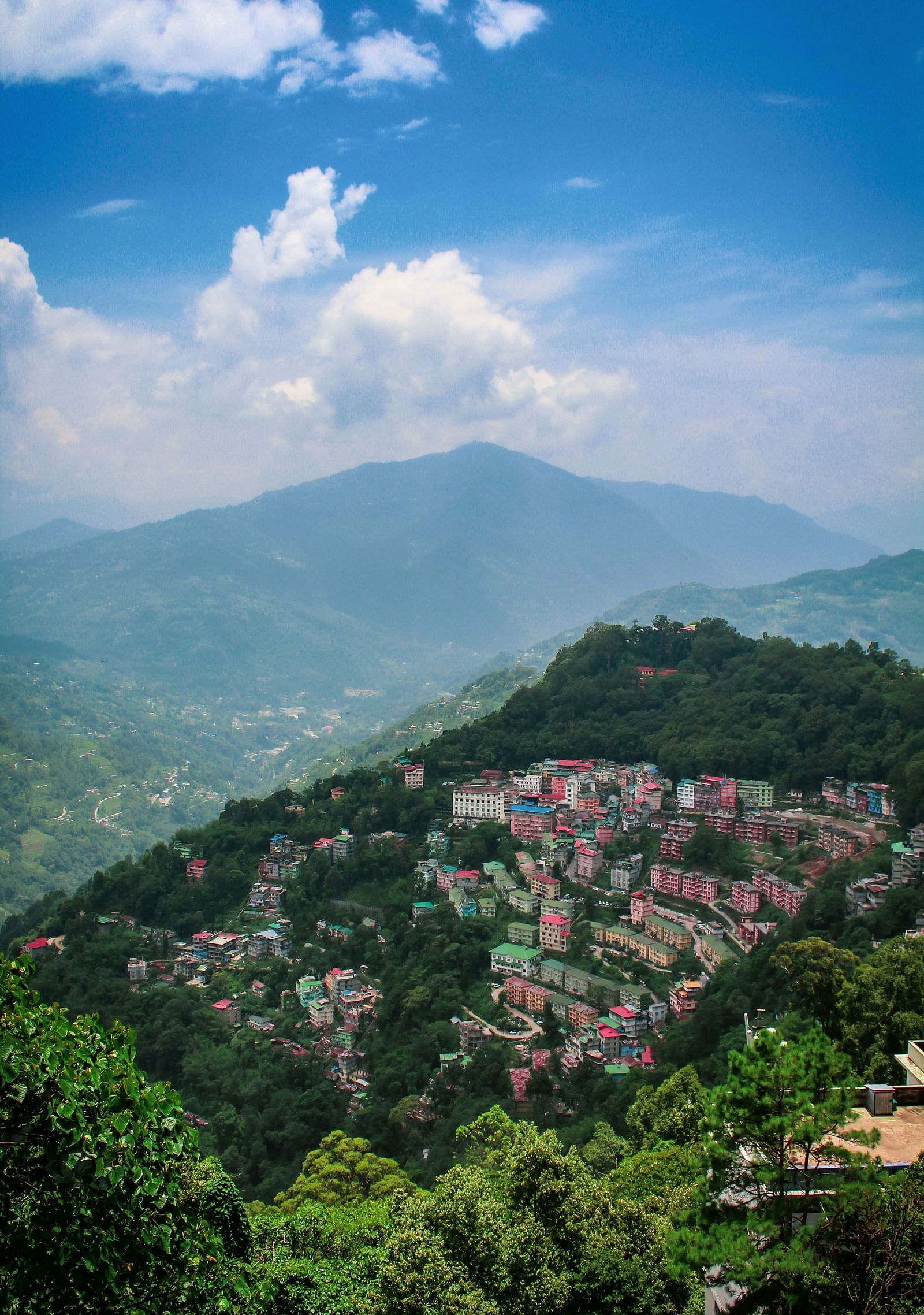  An aerial view of a town nestled in the green hills under a blue sky