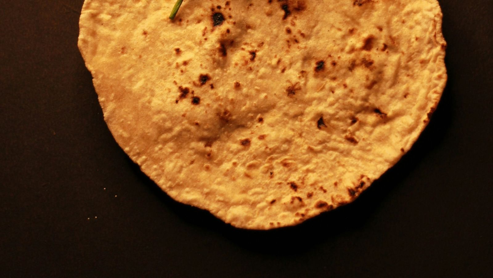 Top view of a roti with green chillies kept on top of it