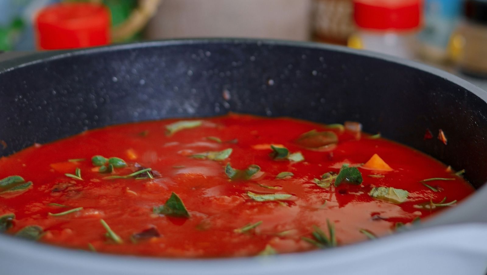 An image of a bowl of curry, with potted plants subtly visible in the blurred background.