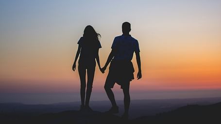 Two people holding hands against a golden sky