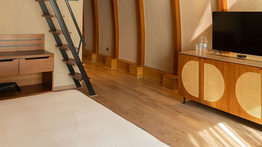 A high ceiling room with a bed, TV, and a stairs to the second deck at Ananta Spa and Resort, Ajabgarh