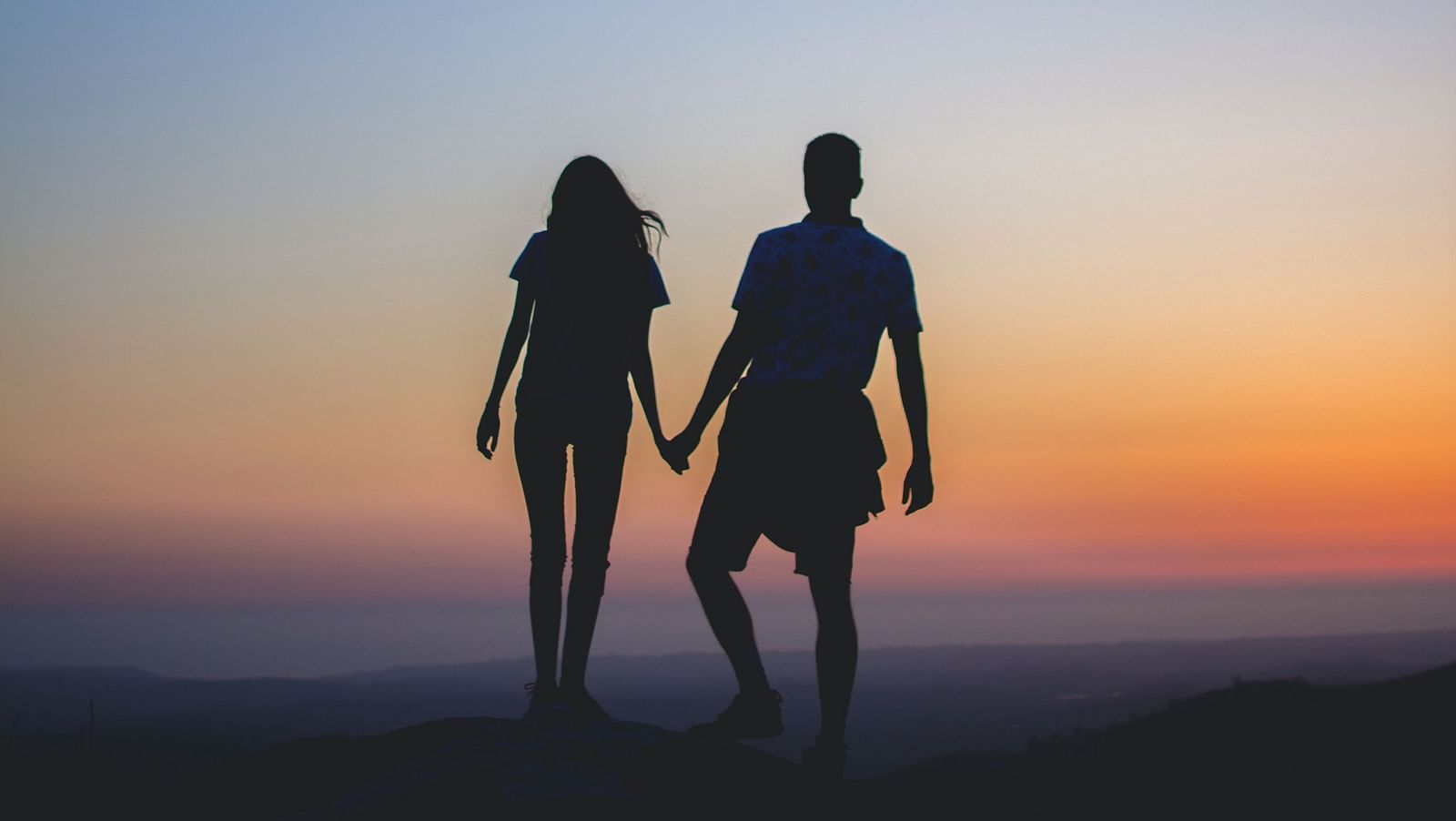 an image of a  couple holding hands as they watch sunset