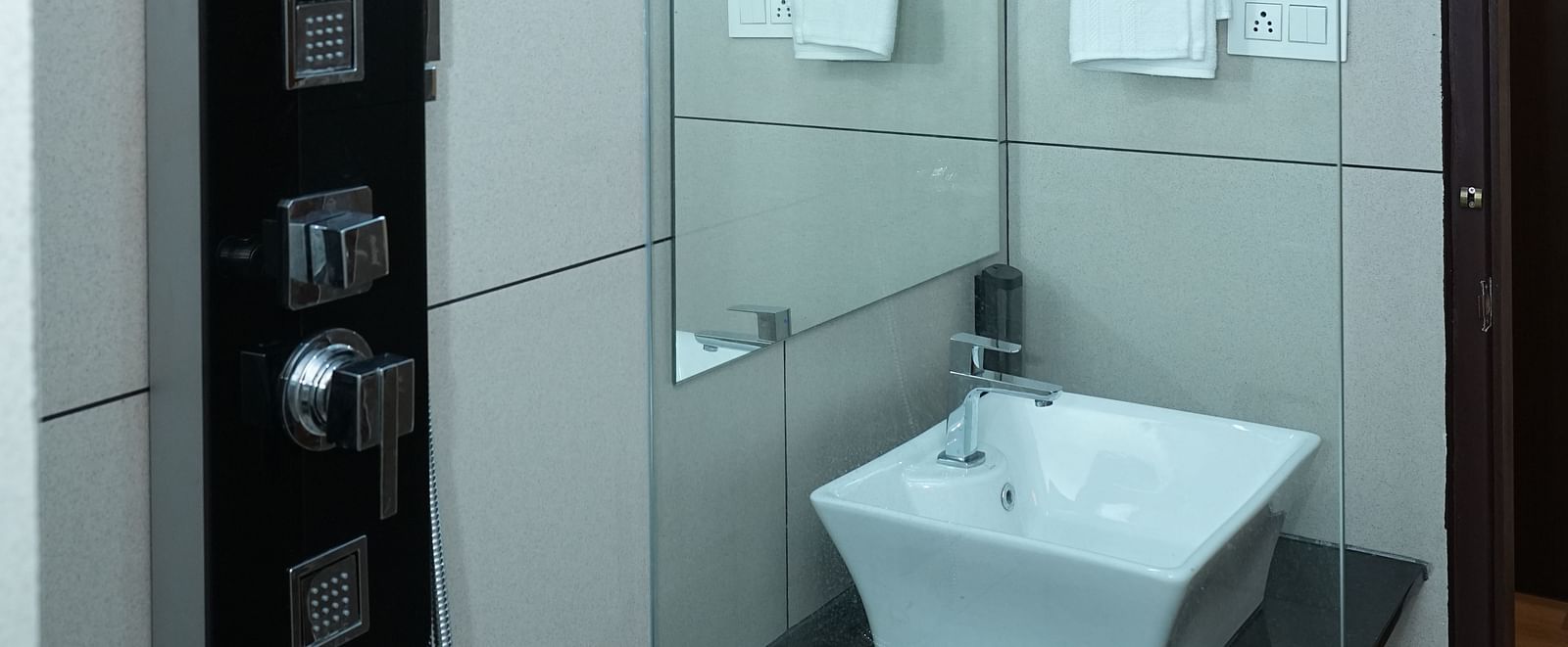 a washroom featuring the standing shower along with the washbasin separated by a glass partition - Hotel Grand Sigma