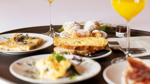A tray with food and beverages placed on a bed