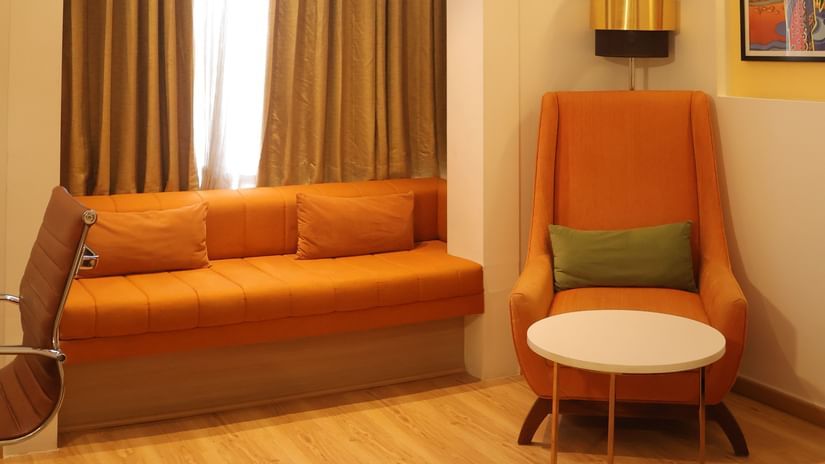 A sitting area with a couch, a coffee table and a sofa chair near the window at the Best Western, Vrindavan