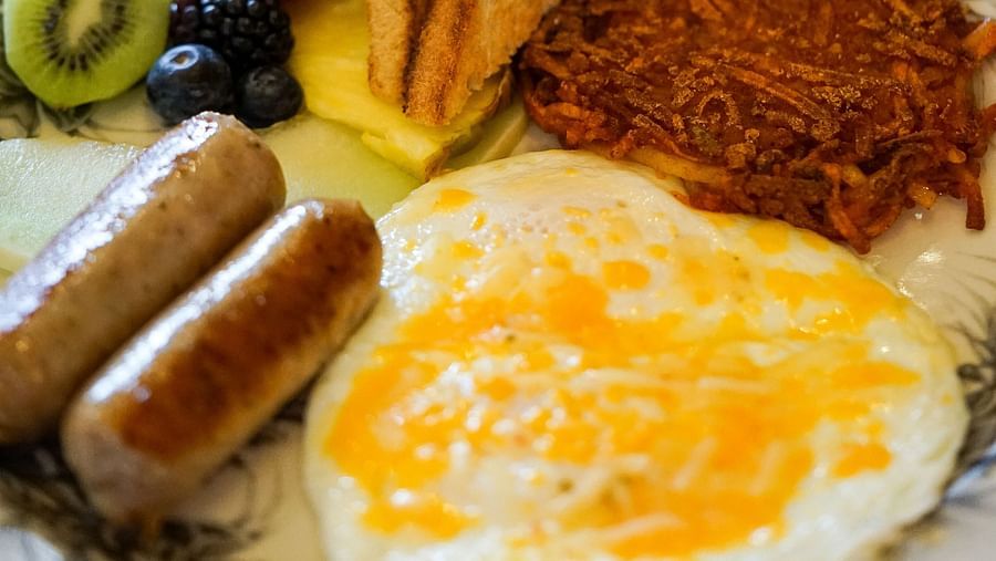 A wholesome breakfast plate with scrambled eggs, toasted bread, grilled sausage, and fresh fruit - Brewery Gulch Inn & Spa