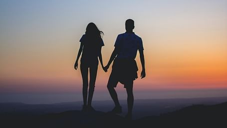 a couple holding hands in a silhouette setting after the sunset