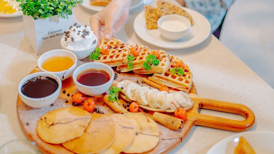 A woman enjoying her meal at a table filled with a variety of delicious dishes at Crescent Spa & Resort, Indore