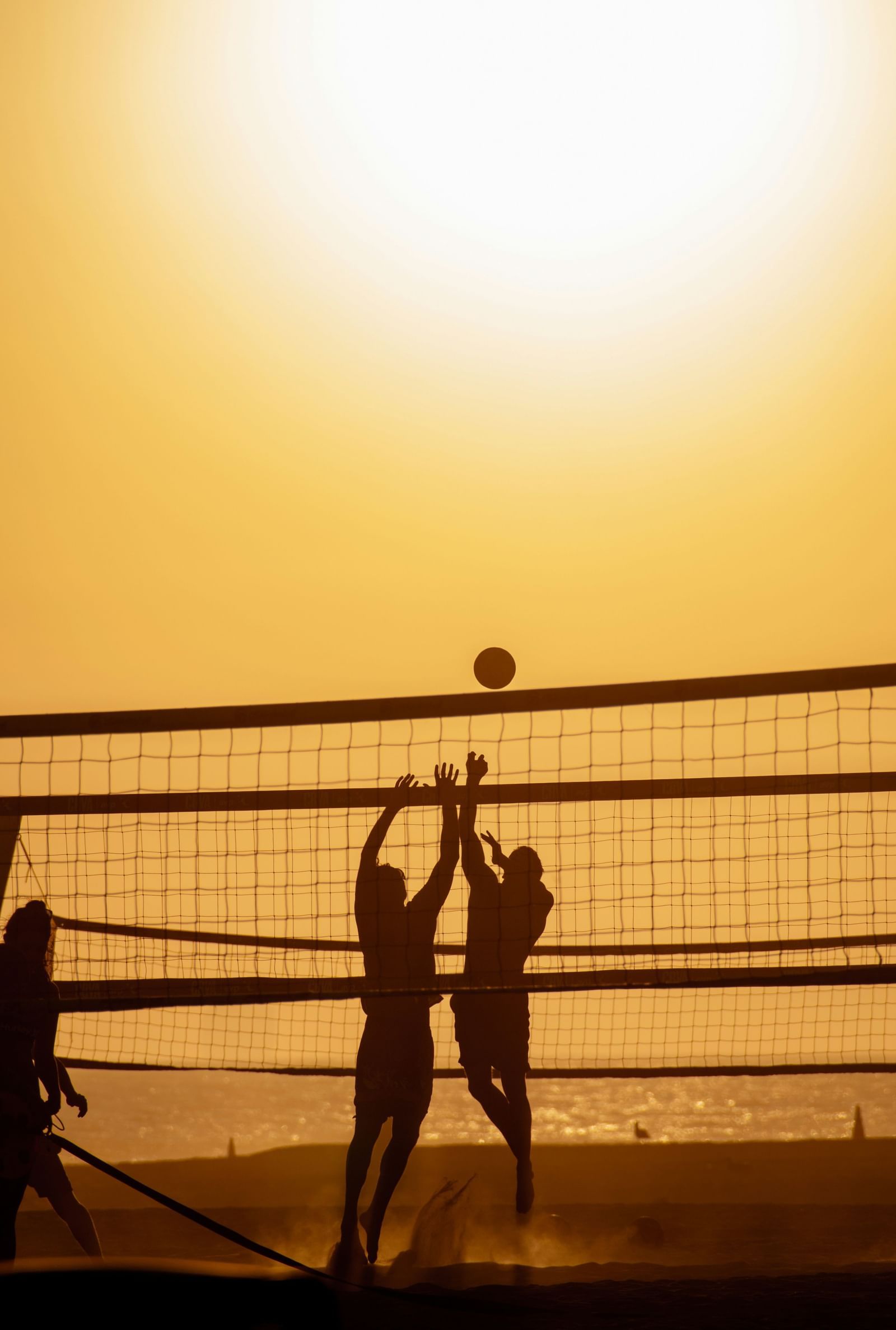 An image of two people playing volleyball by the beach