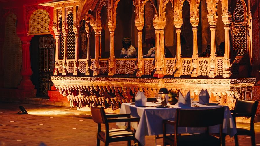 Night view of a dining area with tables and chairs with a clear sky in the background at Surpura Bagh.