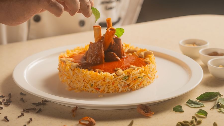 A close-up of a happy chef garnishing a meal on a plate at The Ananta Udaipur, adding final touches with a smile.