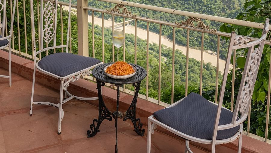 an open sitting area with a table set for two with views of the mountains at Neer Ganga Resorts