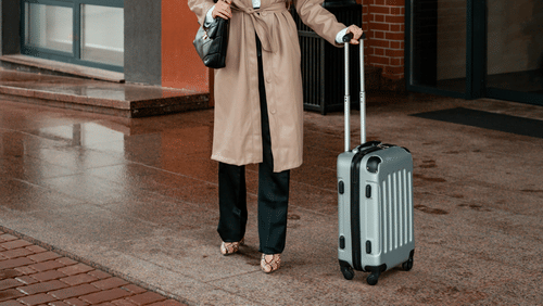 A woman holding a suitcase while standing outdoors.