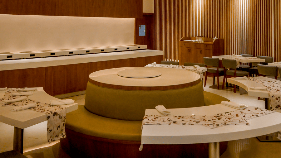 An indoor restaurant dining area features a large circular seating booth beneath a round glowing chandelier light fixture at Tiara by MPS.
