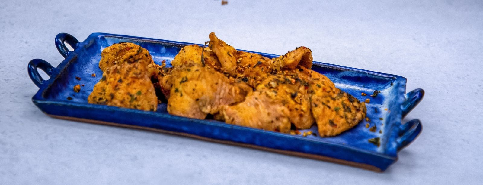 A hand sprinkling something on a tray of appetiser at The Hamuse Hotel, Kodaikanal.