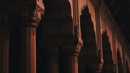 An overview of the entrance to an old building with arches on top and columns in view as well.