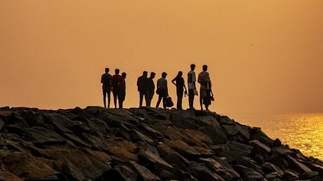 a group of people standing on boulders near Auroville Beach in Pondicherry