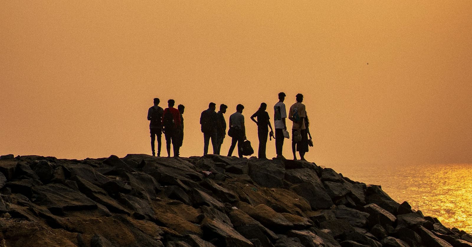 a group of people standing on boulders near Auroville Beach in Pondicherry