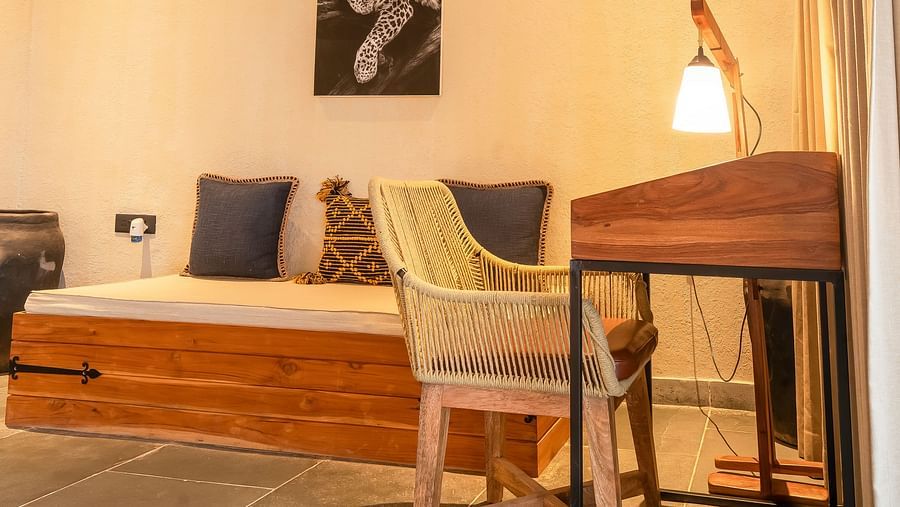 An image of a living area featuring a work desk and chair, an AC, a sofa, and some decorative elements at Kurja Jawai