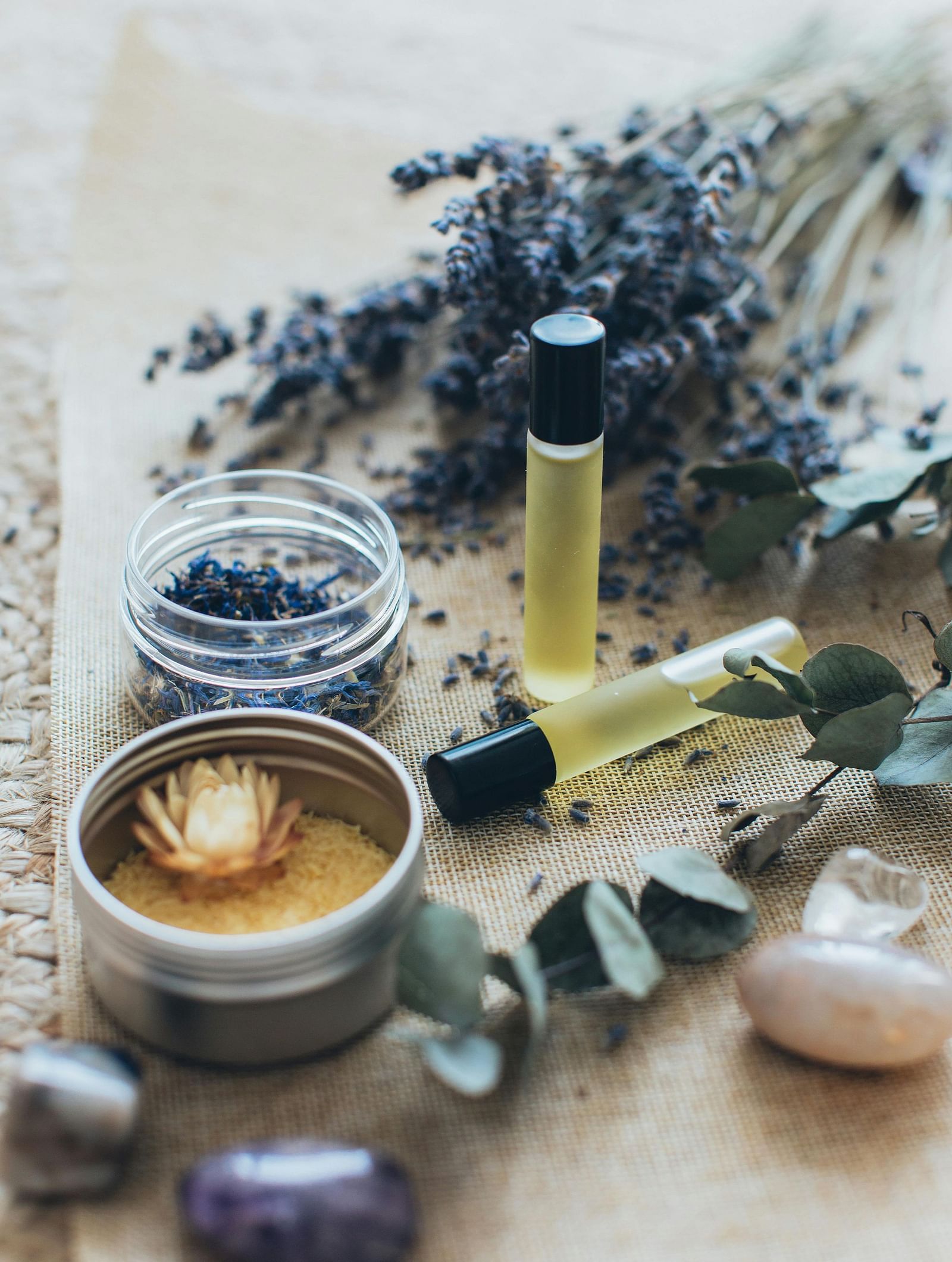 A collection of spa treatment ingredients, including dried lavender, essential oils, and a candle.
