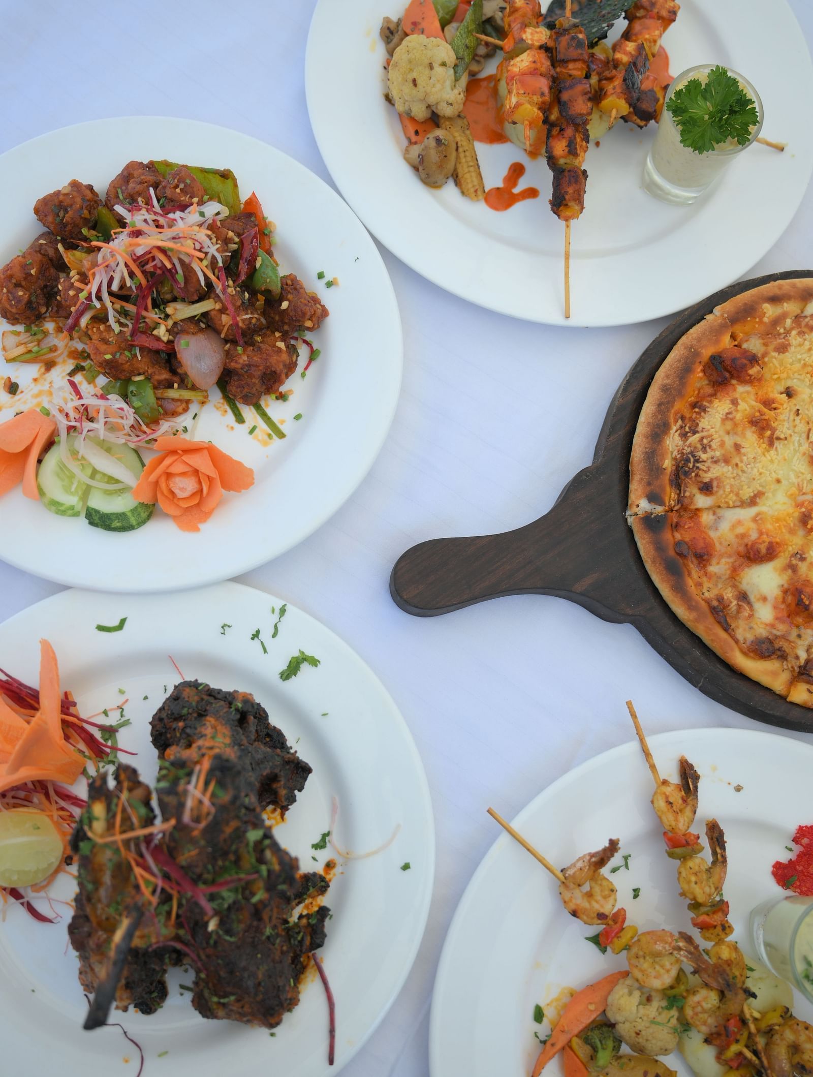 An appetizing array of various dishes, including kebabs and a pizza, ready to be enjoyed at Royal Comfort Regency.
