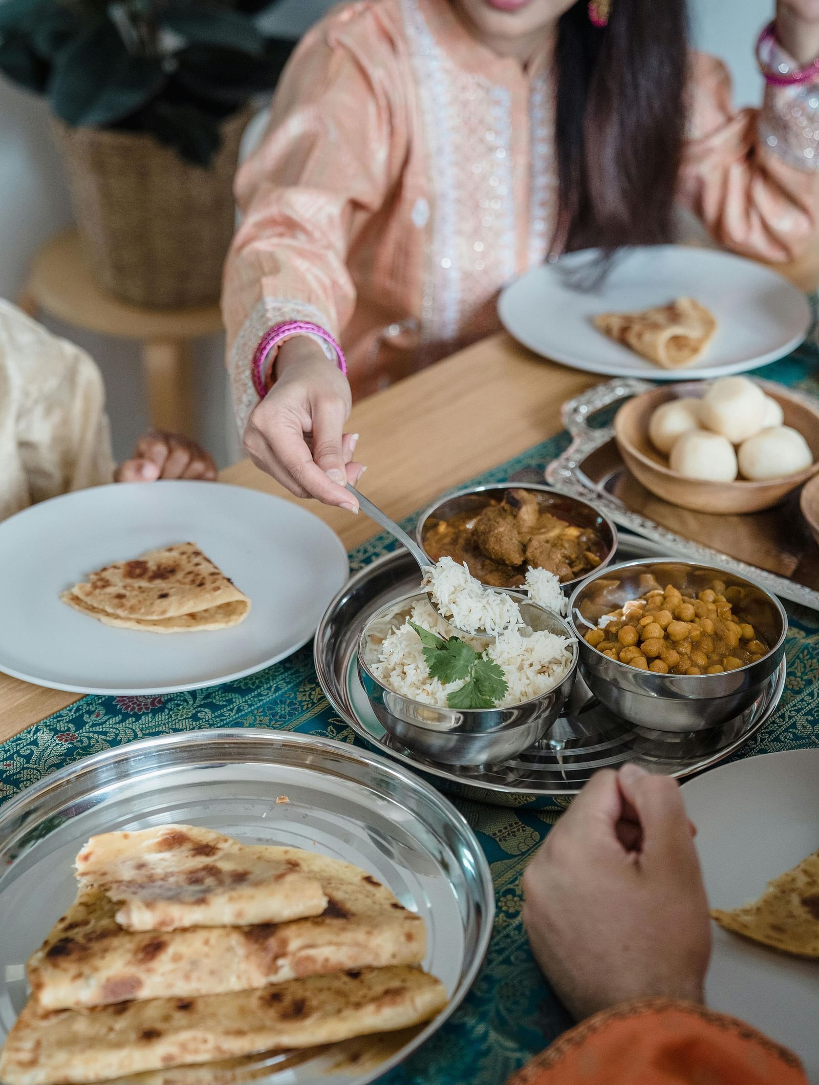 People sharing a meal with various dishes on a table, including flatbread and small bowls of food.