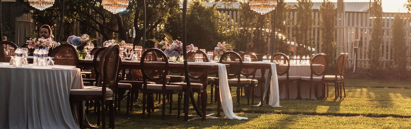Outdoor dining area at sunset with string lights and banquet tables.