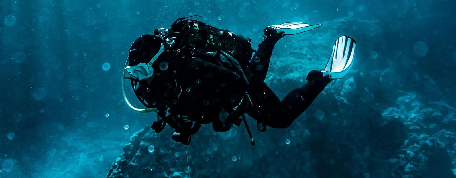 An overview of a person scuba diving with the sun's rays shining down.