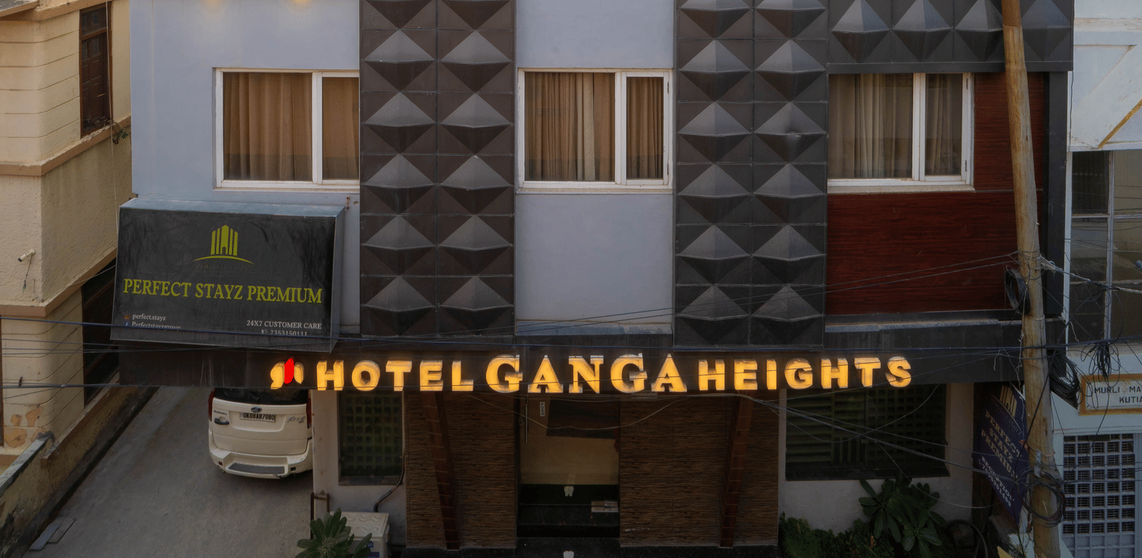 Exterior of the modern hotel building with red and grey panelled facade - Perfectstayz Premium at Har Ki Pauri Road (Ganga Heights)