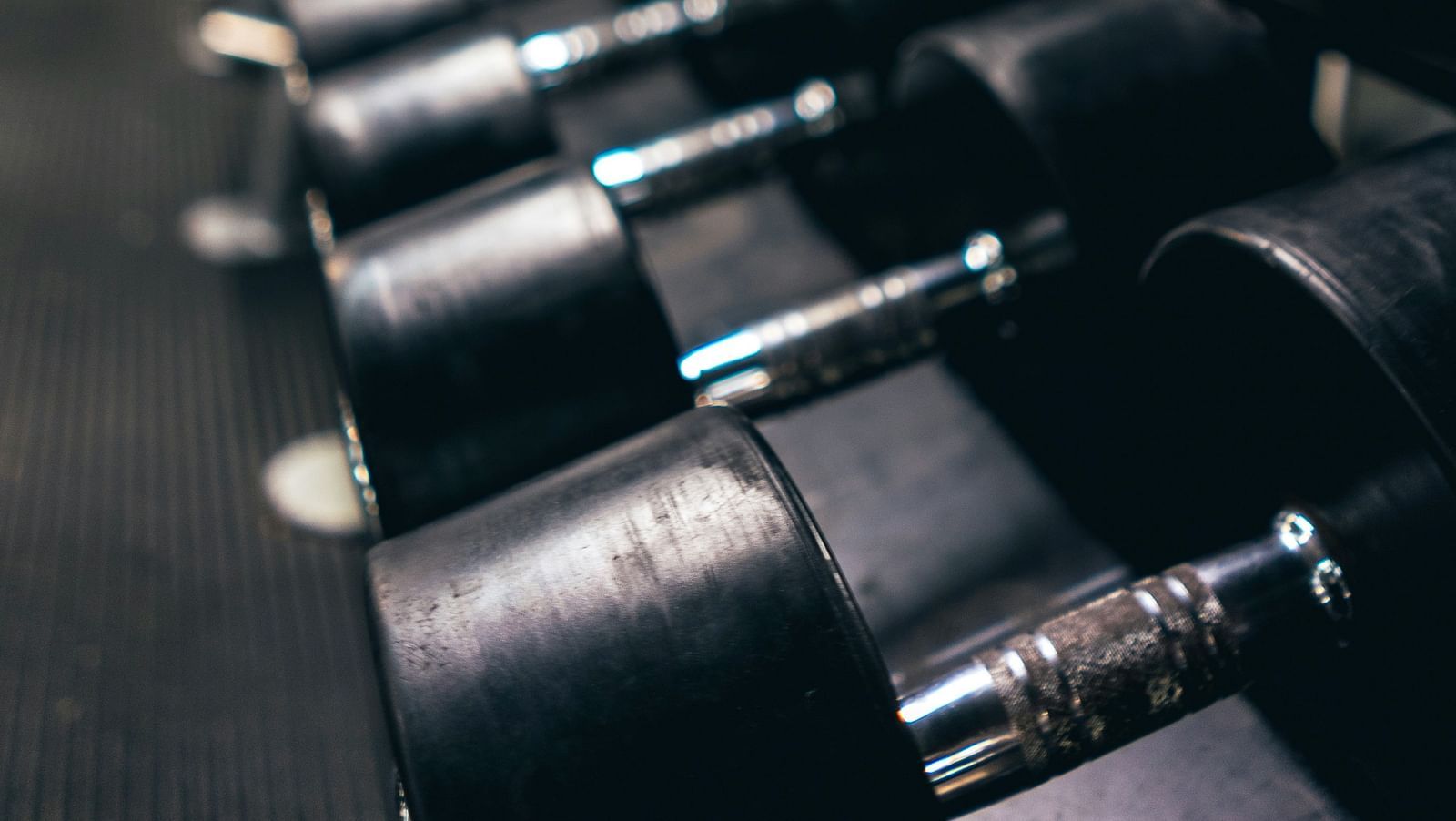 Row of black dumbbells neatly arranged in a modern fitness centre.