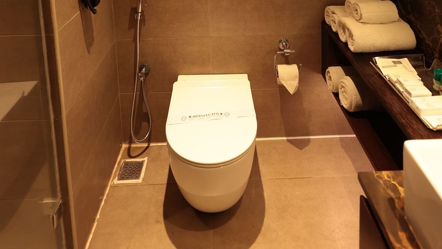 A washroom with a western toilet and a wall-mounted mirror to the side | Cenneys Gateway