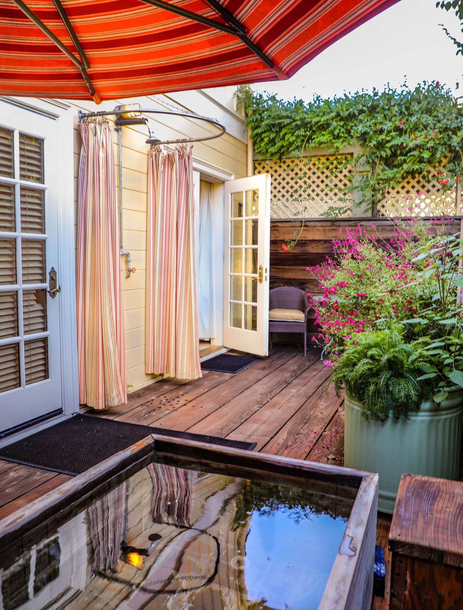 A private patio at the Tallman Hotel contains a wooden deck, an umbrella, and a small water feature.