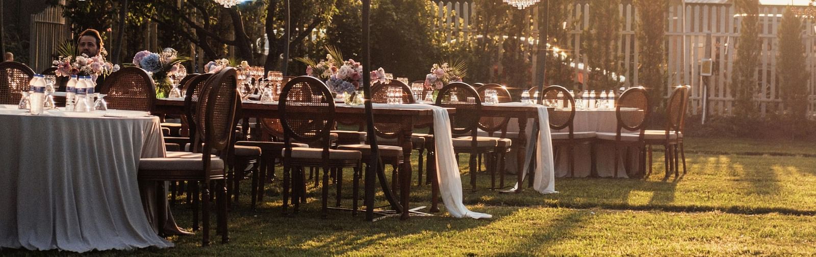 Outdoor dining area at sunset with string lights and banquet tables.