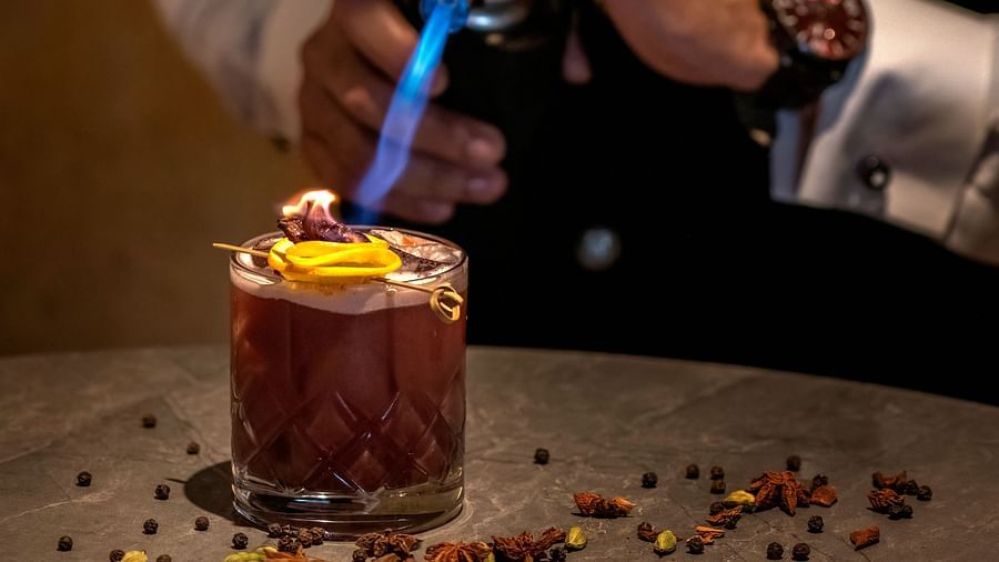 image of the bartender lighting up a beverage served at the aura bar - The Claridges New Delhi
