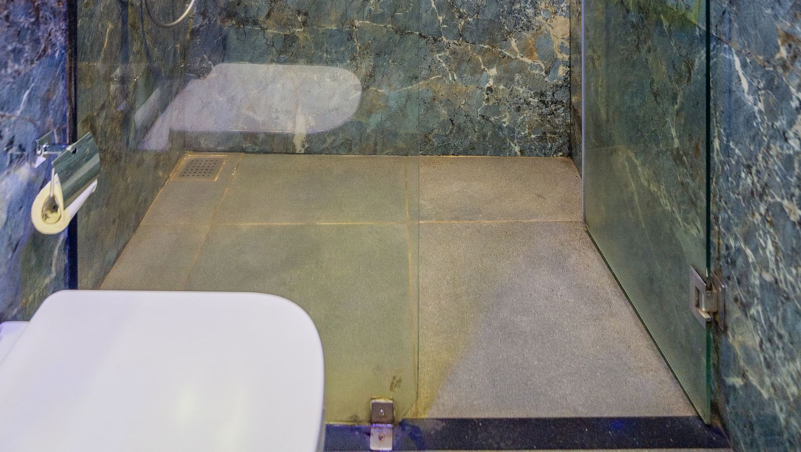 Image of a washroom with a shower area separated by glass at Hotel Altitude, Madikeri.