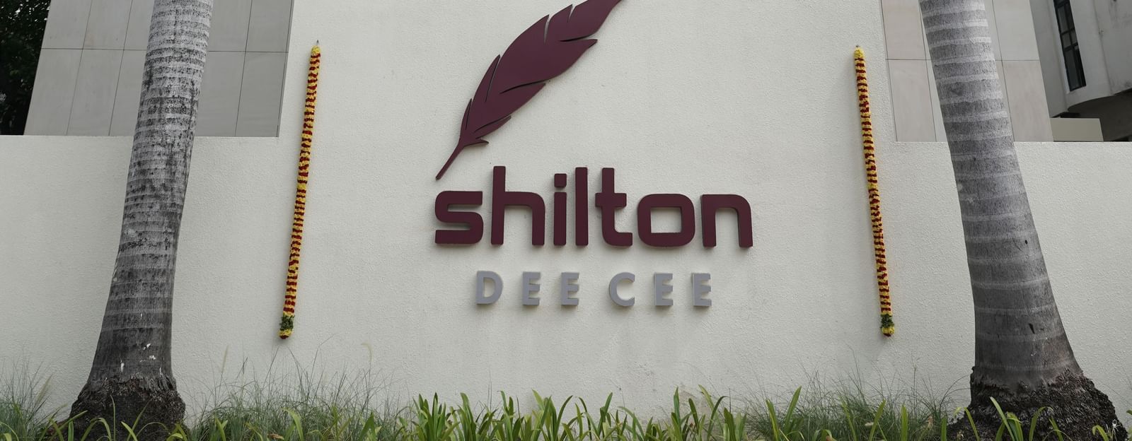 A portrait image of Shilton Hotel's facade surrounded by towering coconut palm trees