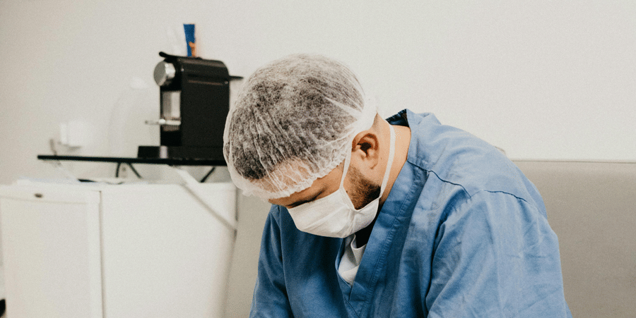 A Mail nurse in scrubs sitting in a chair, facing d