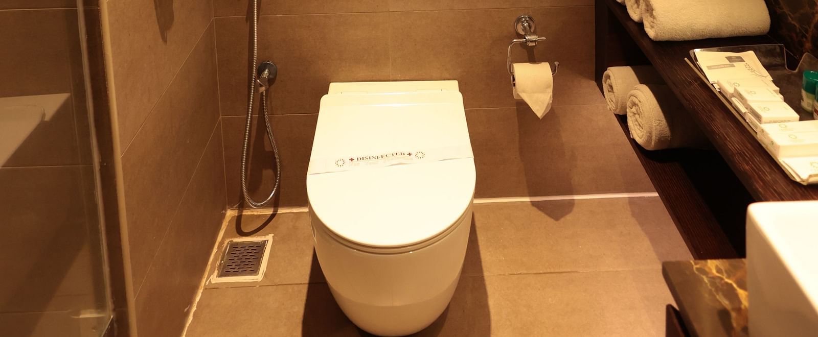 A washroom with a western toilet and a wall-mounted mirror to the side | Cenneys Gateway