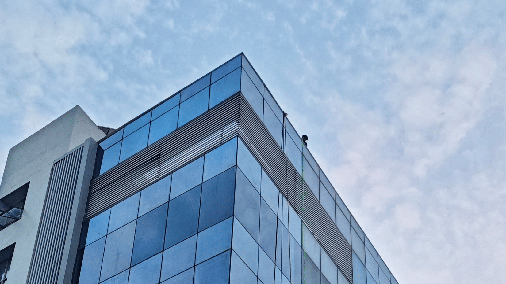 A tall glass sky scrapper with the blue sky above it.